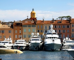 Yachts moored in the port of St Tropez with the iconic clock tower in the background.